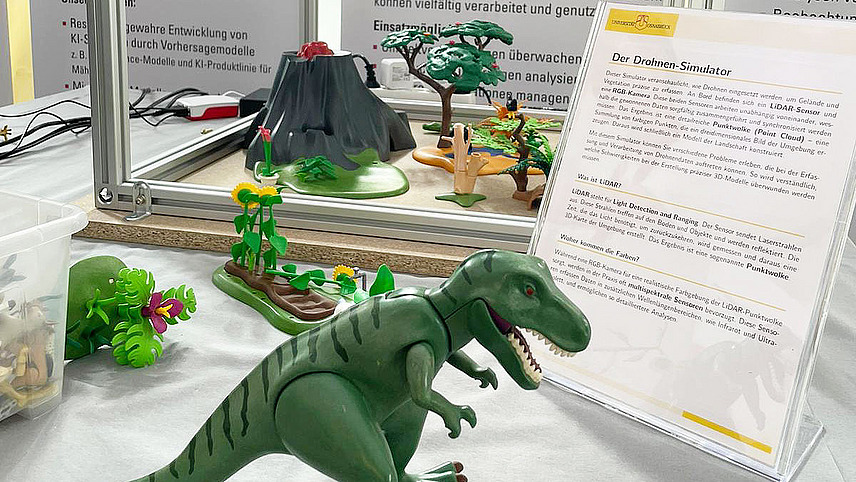 Close-up of a research poster on the topic of drone simulation. A toy dinosaur stands in the foreground.