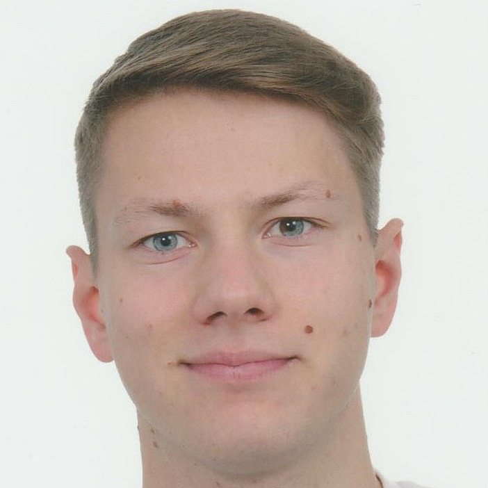 Bild des Geischtes eines jungen Mannes mit kurzen brauen Haaren.