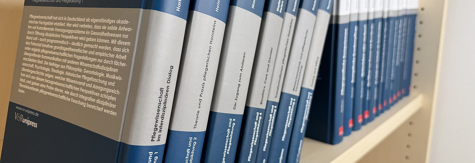 Mehrere in Fachb&uuml;cher in blauen Buchumschl&auml;gen des Universit&auml;tsverlags stehen ordentlich nebeneinander in einem Regal.