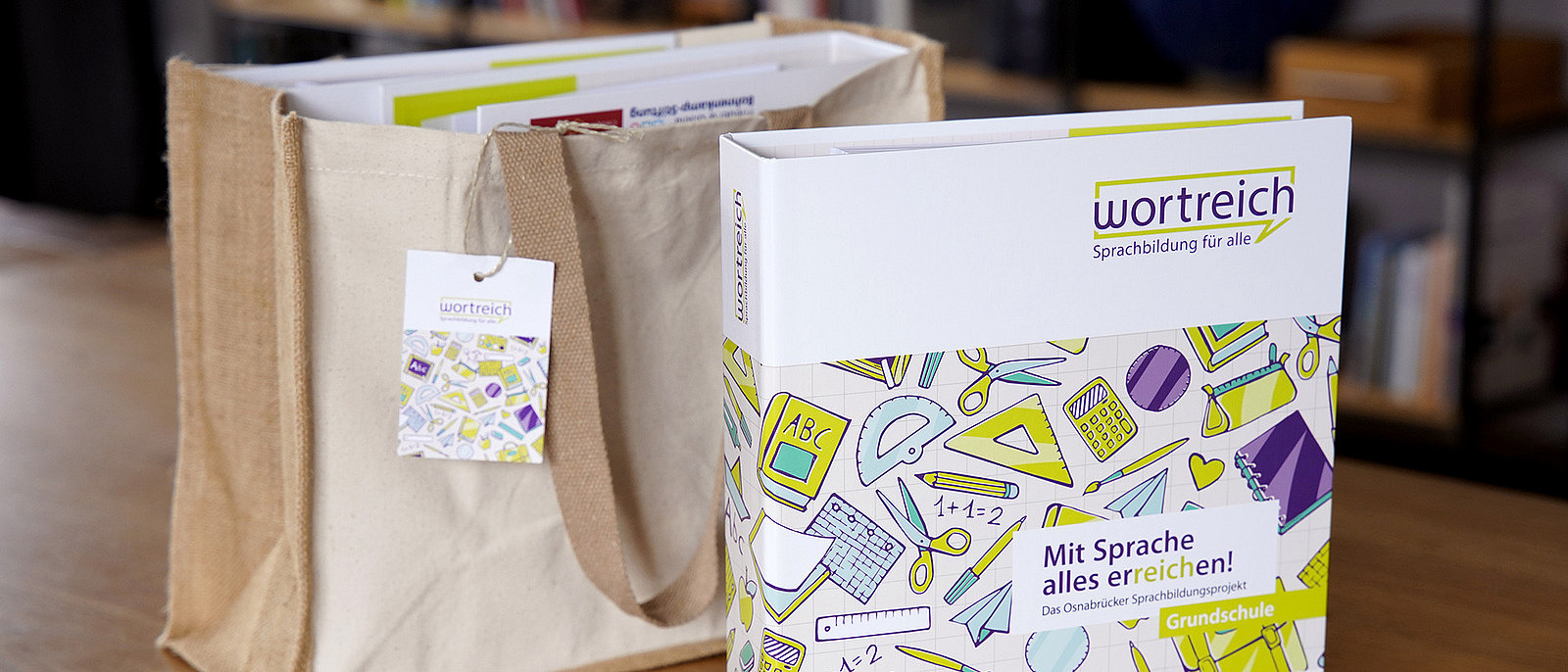 Ein Wortreich-Ordner steht vor einer Stofftasche, in der weiteres Material enthalten ist.