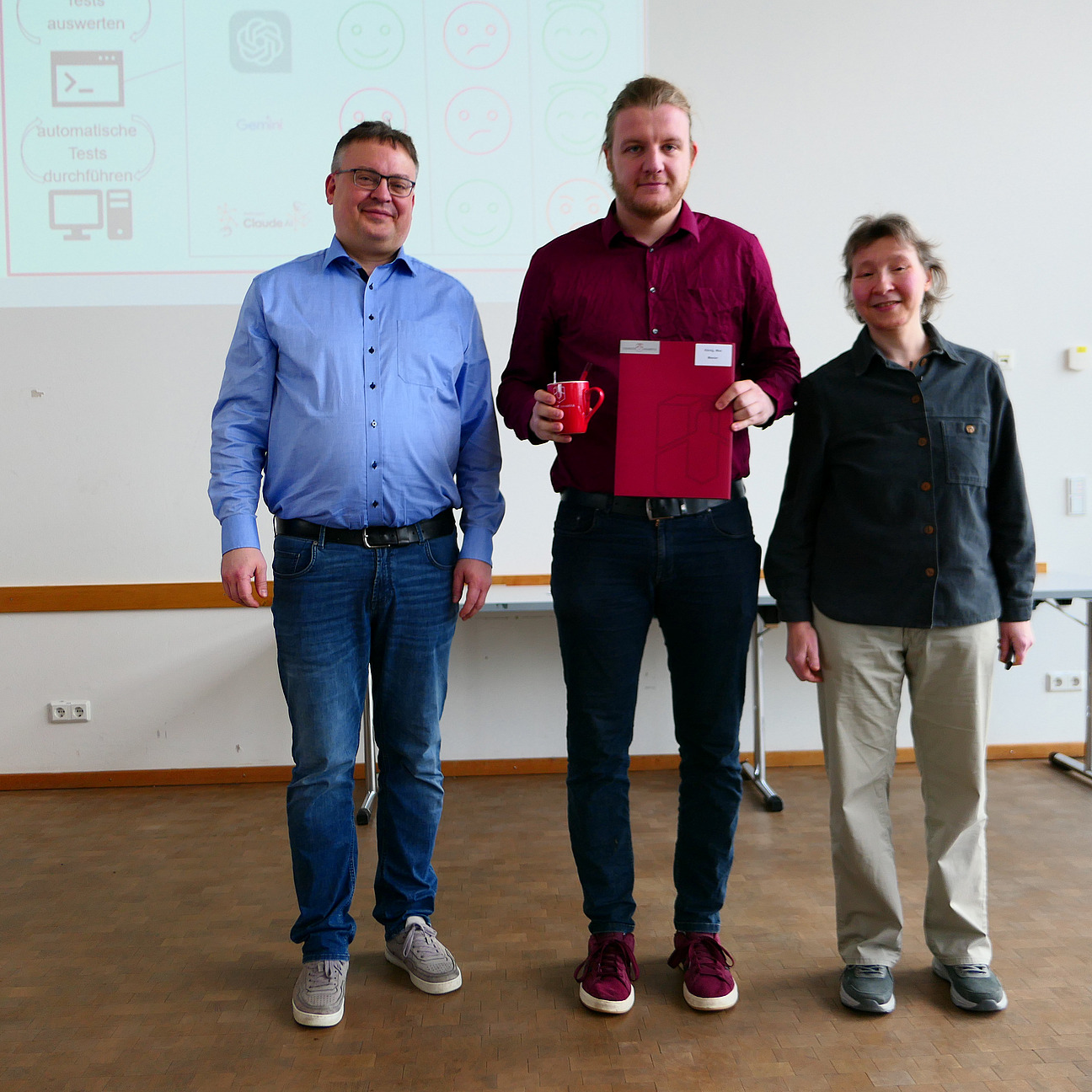 A student stands between the dean and the dean of studies with his degree certificate.