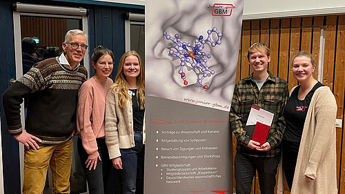 F&uuml;nf l&auml;chelnde Personen, die zweite Person von rechts h&auml;lt eine Urkunde.