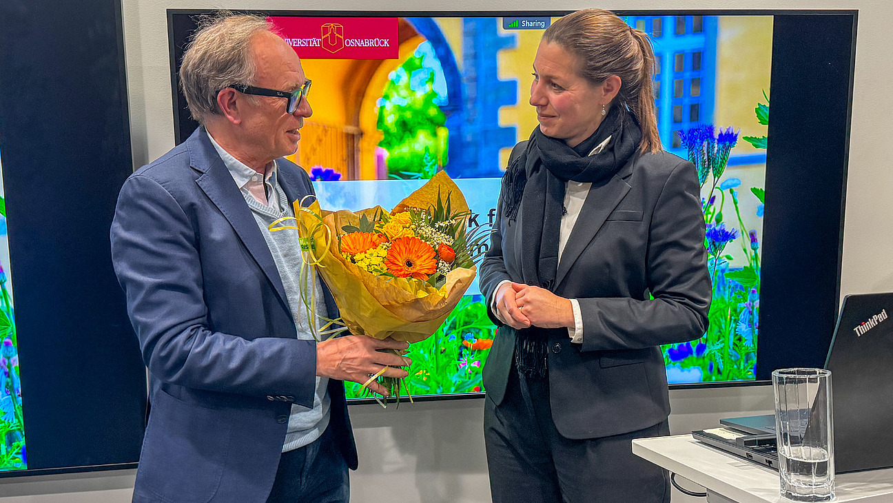 Eine Mann und eine Frau im Gespr&auml;ch, der Mann h&auml;lt einen Blumenstrau&szlig; in der Hand