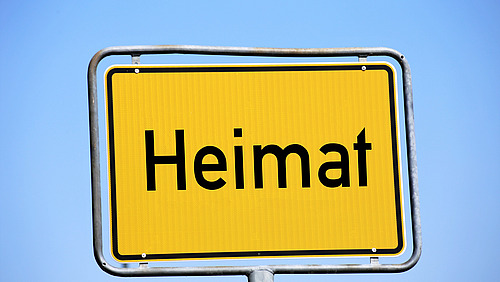 Ein gelbes Straßenschild mit dem Wort "Heimat".