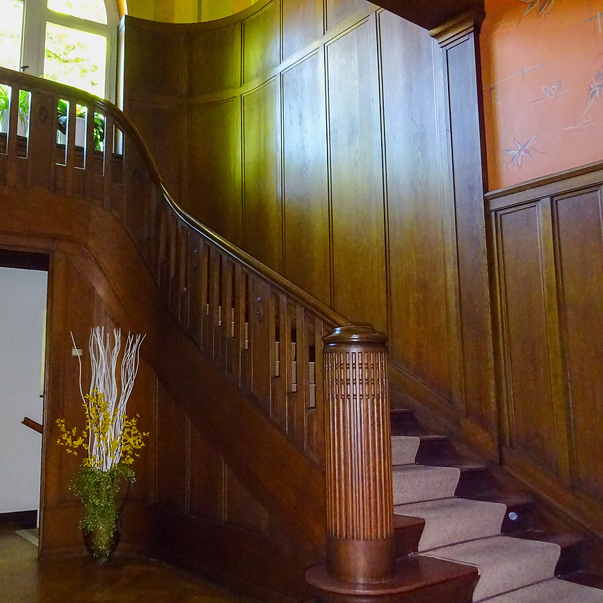Das stilvolle und licht-durchflutete Treppenhaus des G&auml;stehauses, mit Holztreppe und zahlreichen Wandelementen aus Holz sowie der grossen Fensterfront auf der Empore.