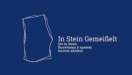 Vor einem dunkelblauen Hintergrund ist eine stilisierte, weiße Umrisszeichnung eines Steins. Rechts daneben stehen in weißer Schrift die Worte "In Stein Gemeißelt", gefolgt von den Übersetzungen: "Set in Stone" (Englisch), "Высячаны ў камені" (Belarussisch) und "Izcirsts akmenī" (Lettisch)