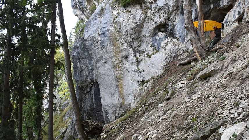 Das Foto zeigt einen Steilhang im Gebirge, an dem eine Ausgrabung stattfindet
