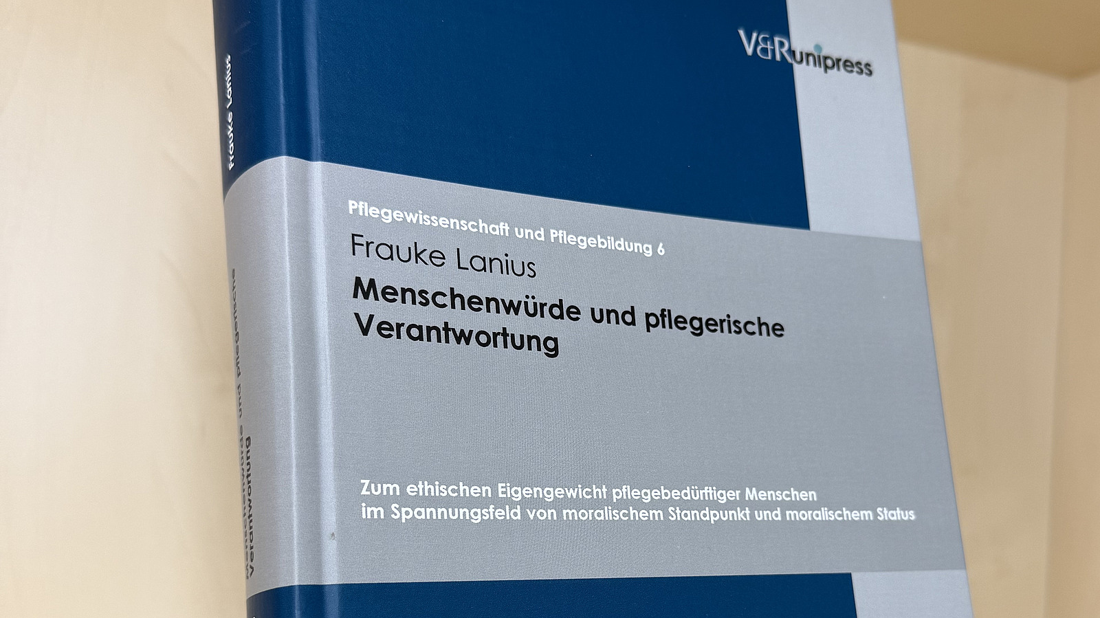 Ein Fachbuch von Frauke Lanius mit dem Titel "Menschenw&uuml;rde und pflegerische Verantwortung" steht in einem Regal.