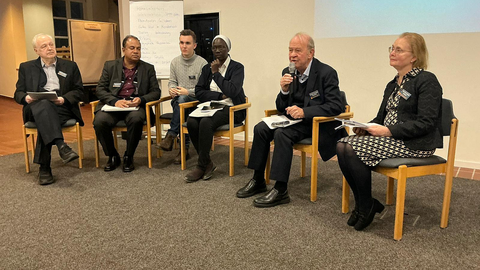 Sechs Personen sitzen in einem Halbkreis.