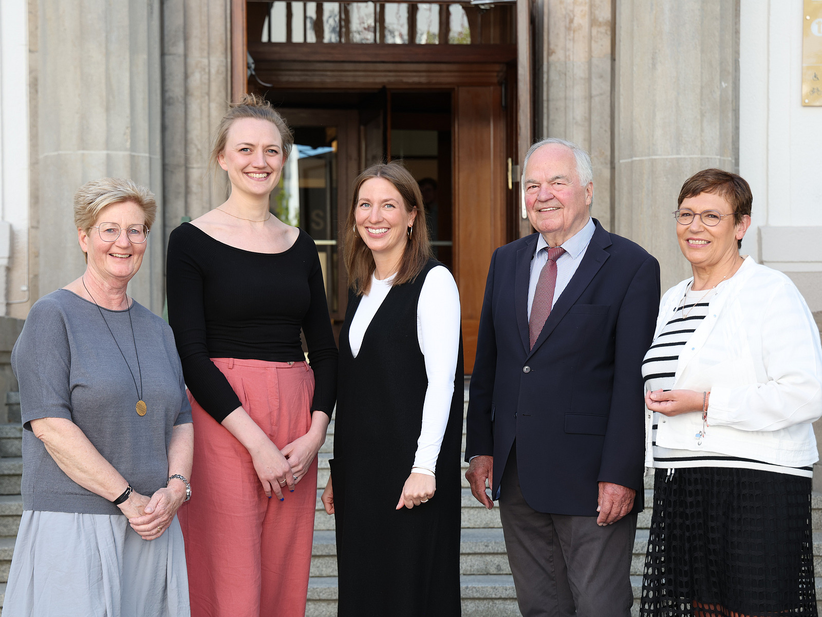 Vier Frauen und ein Mann lächeln in die Kamera.