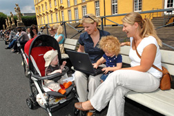 Studierende Eltern mit Kindern und Laptop im Schlossgarten