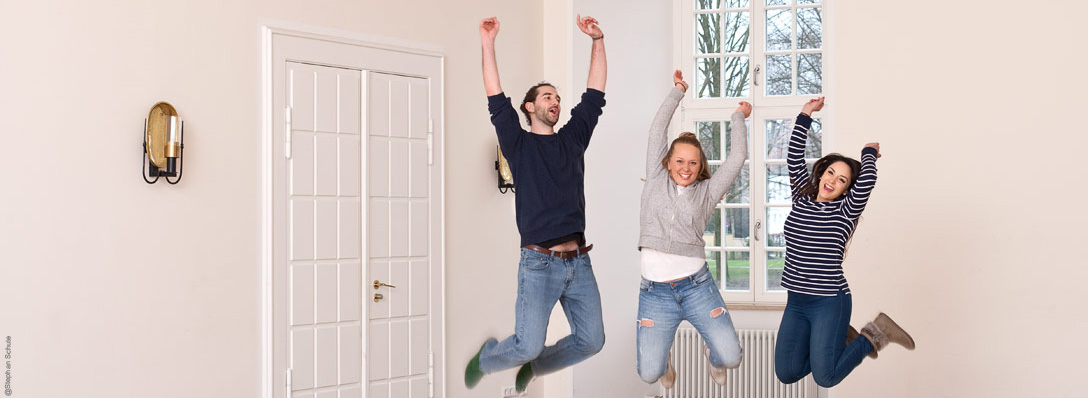 Zwei junge Frauen und ein junger Mann springen vor Freude in die Luft und heben dabei die Hände in die Höhe. Foto: Stephan Schute