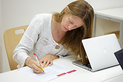 Frau, konzentriert, am Tisch mit Prüfungsblatt. Foto: Universität Osnabrück/Reimar Ott