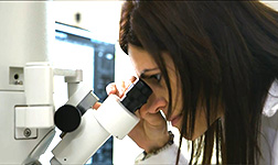 Wissenschaftlerin schaut durch Mikroskop