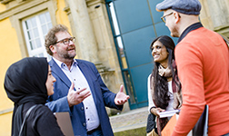 Studierende stehen mit Dr. Michael Kiefer lachend vor dem Osnabrücker Schloss