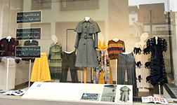 Schaufenster mit textilen Ausstellungsstücken, im Vordergrund Schriftzüge "Universität Osnabrück" und "Textiles Gestalten"