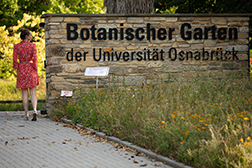 eine Frau schreitet durch den neuen Eingang des botanischen Gartens der Universität