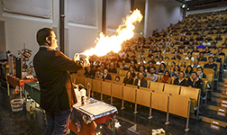 Professor Doktor Marco Breeken erzeugt durch eine Spraydose und ein Feuerzeug eine große Flamme während der Weihnachtsvorlesung.