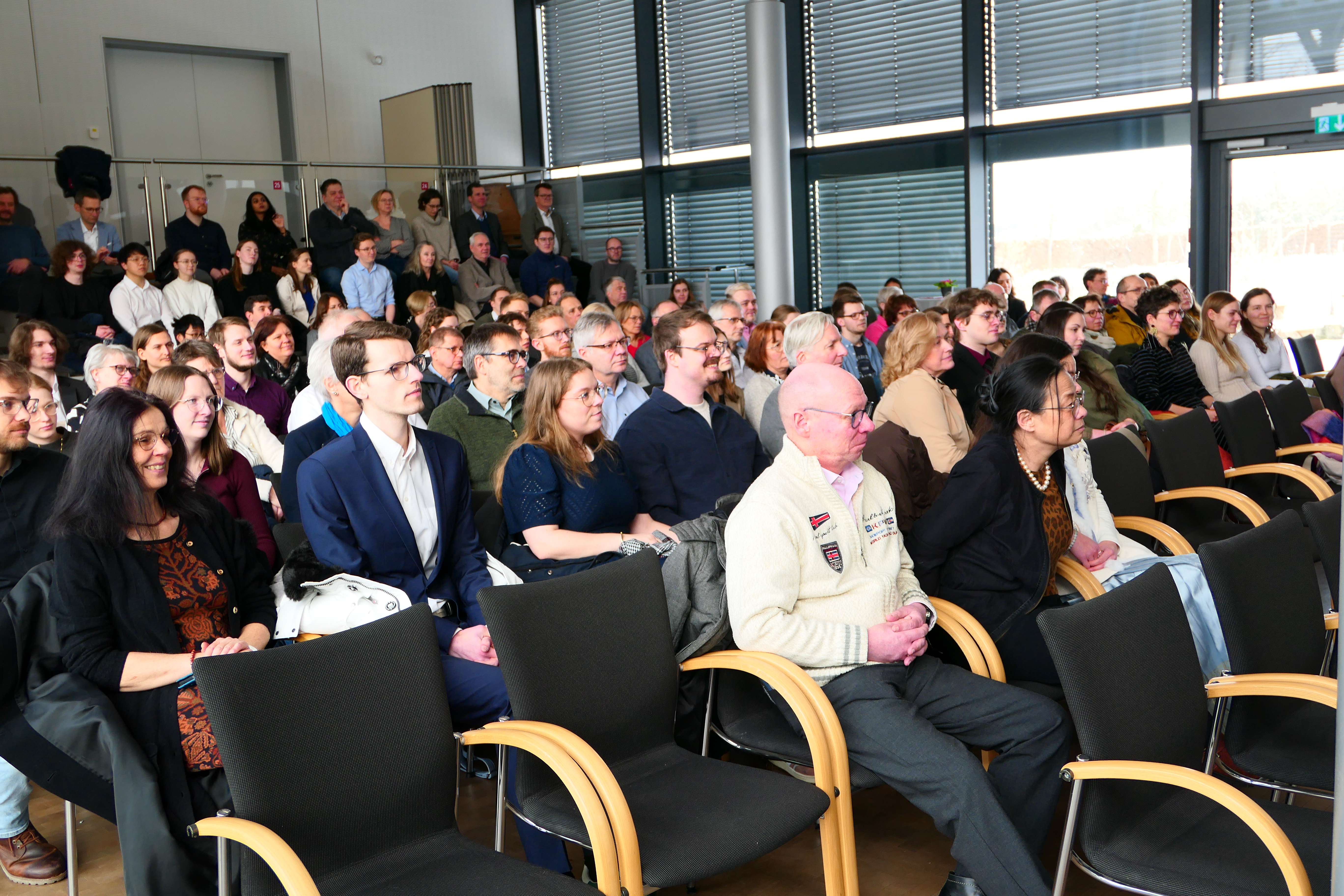 Viele Personen sitzen in Stuhlreihen.