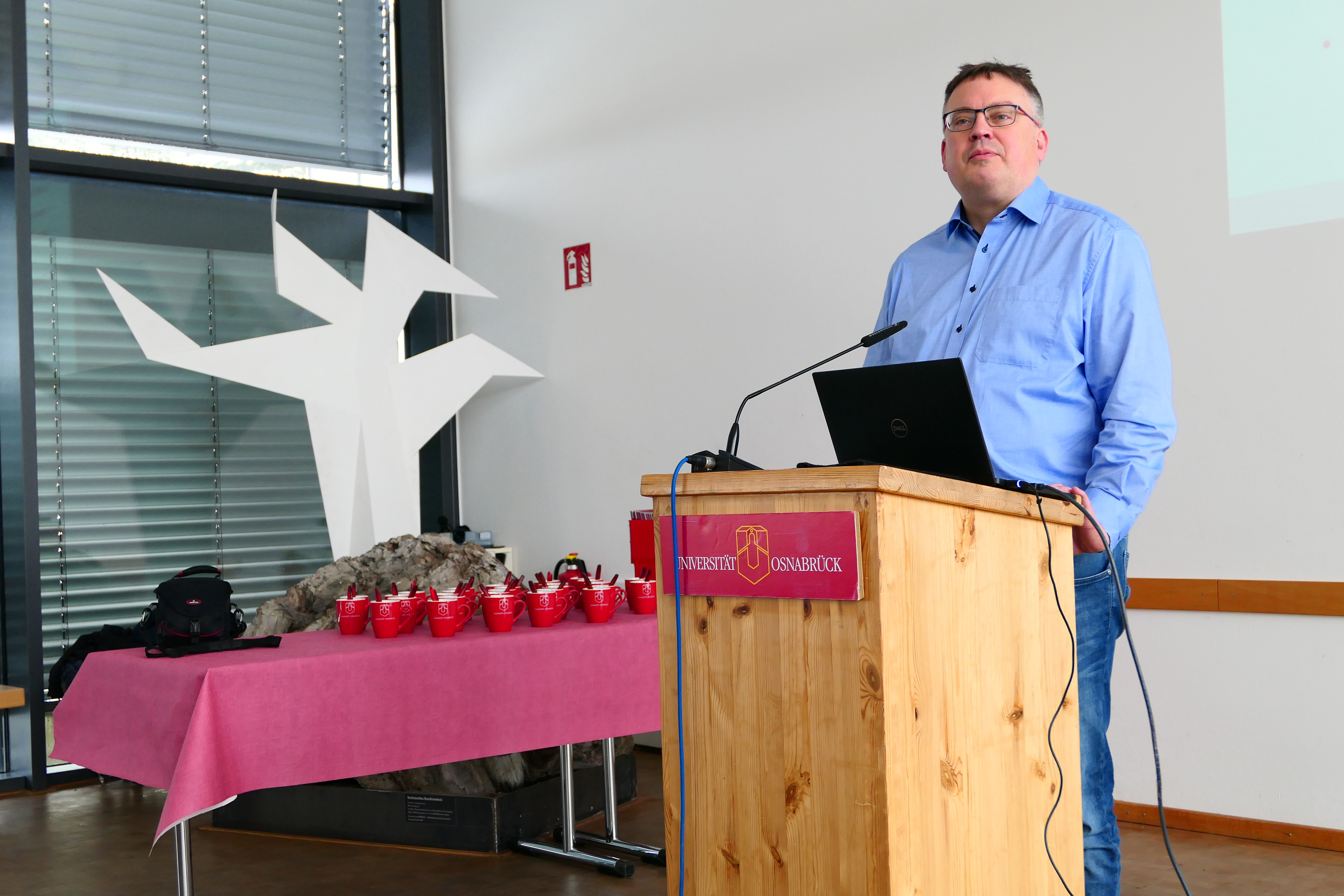 Ein Mann steht an einem Rednerpult der Universit&auml;t Osnabr&uuml;ck.