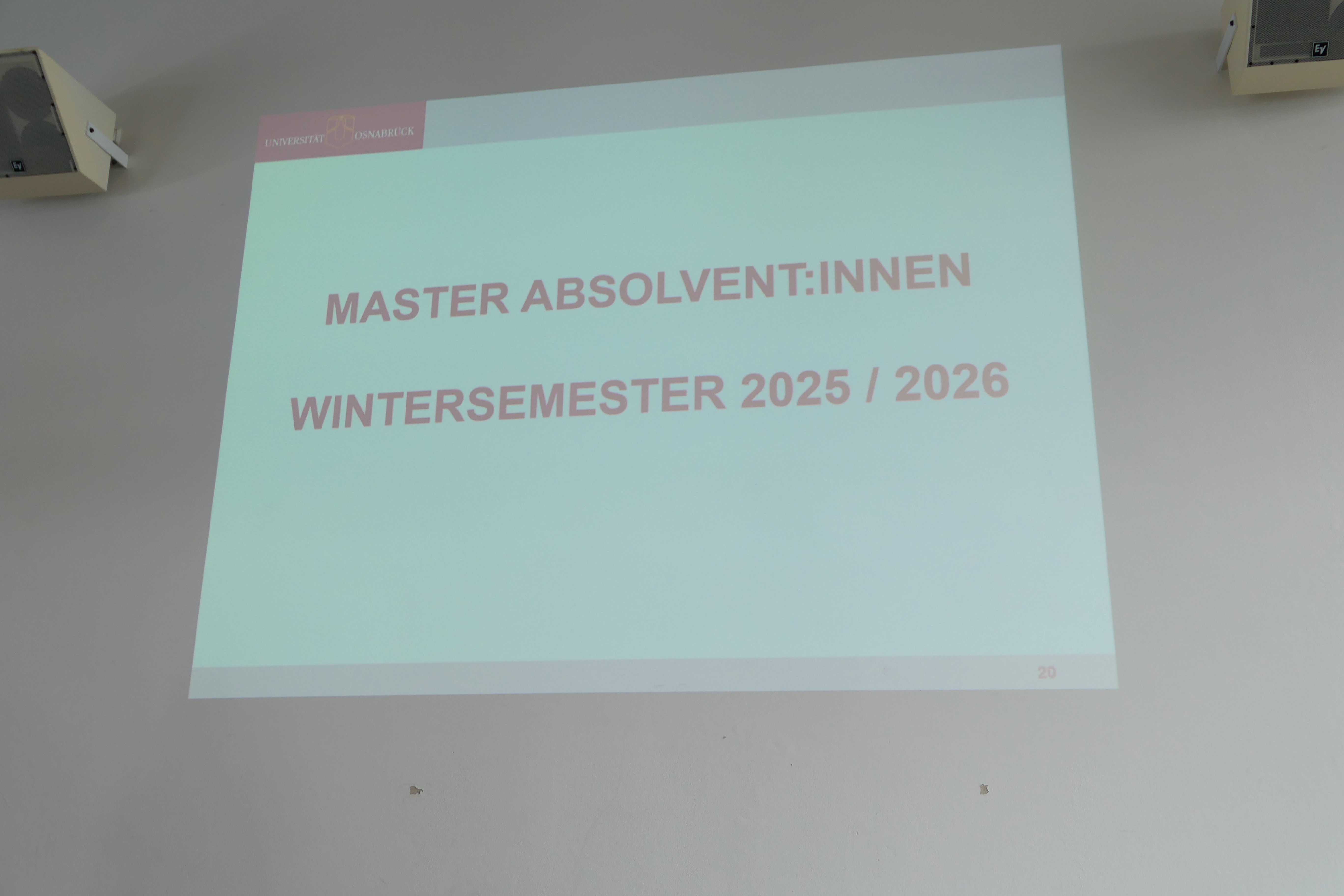Auf einer Projektion steht: "Masterabsolvent:innen Wintersemester 2025/2026".