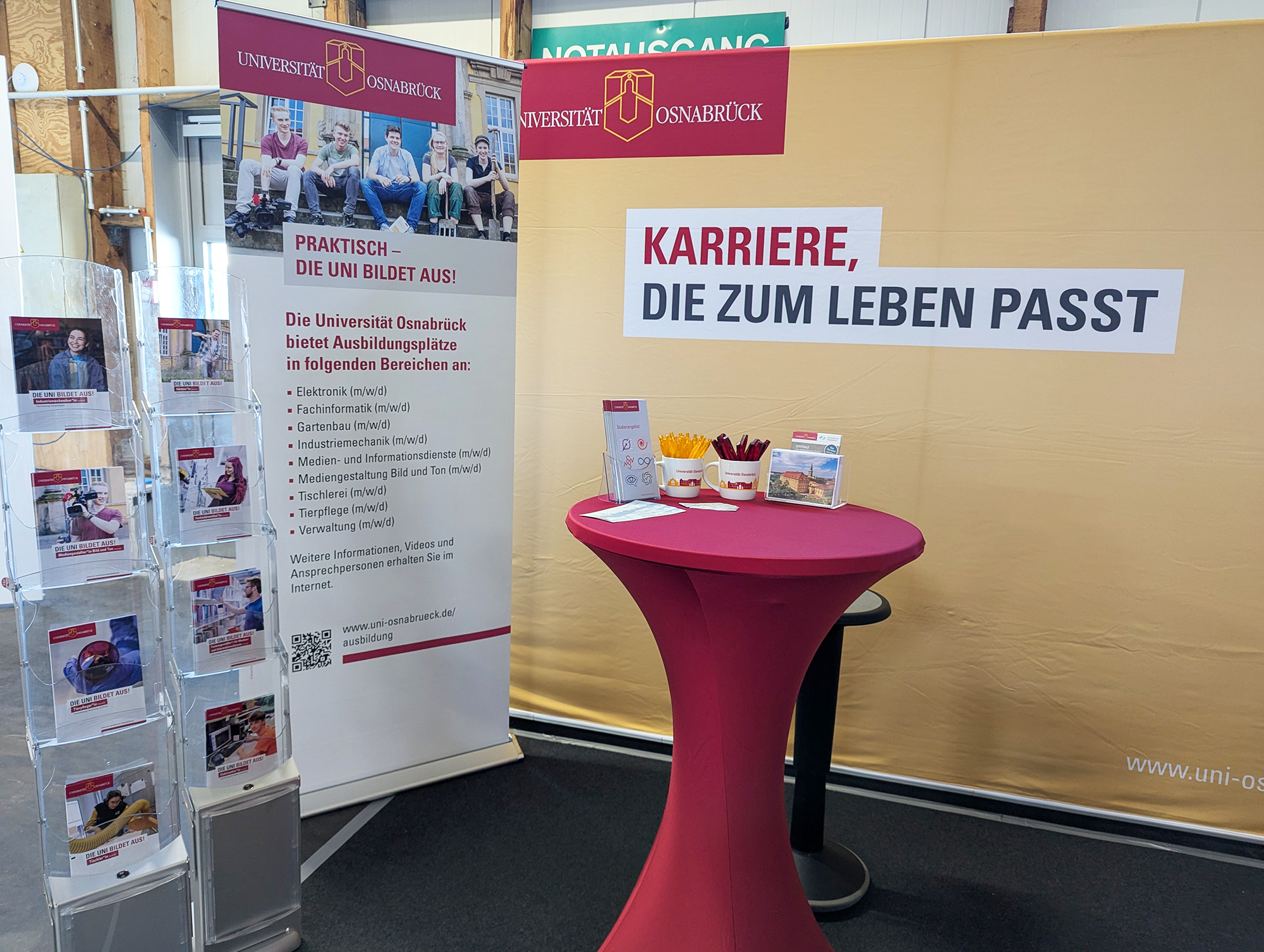 Osnabrück University stand at a trade fair providing information about training opportunities. The focus is on career opportunities that fit in with life and various training areas are presented.
